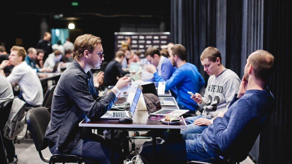 Группа молодых людей за столом с ноутбуками на хакатоне