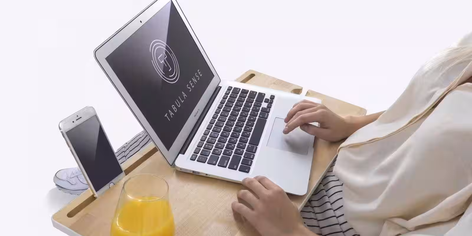 Ноутбук и смартфон на деревянной подставке с планшетом и стаканом сока рядом