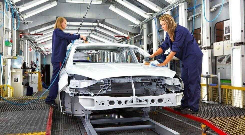 Работницы на конвейере собирают кузов электромобиля Tesla в автозаводе