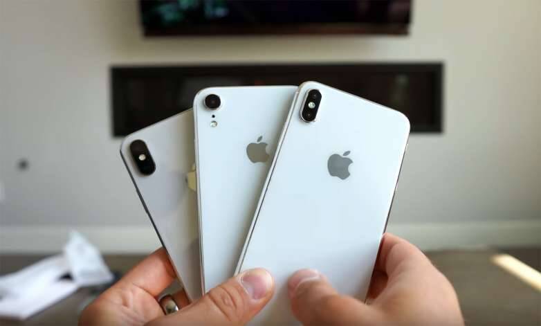 Четыре iPhone XS, XS Max и XR в руке человека
