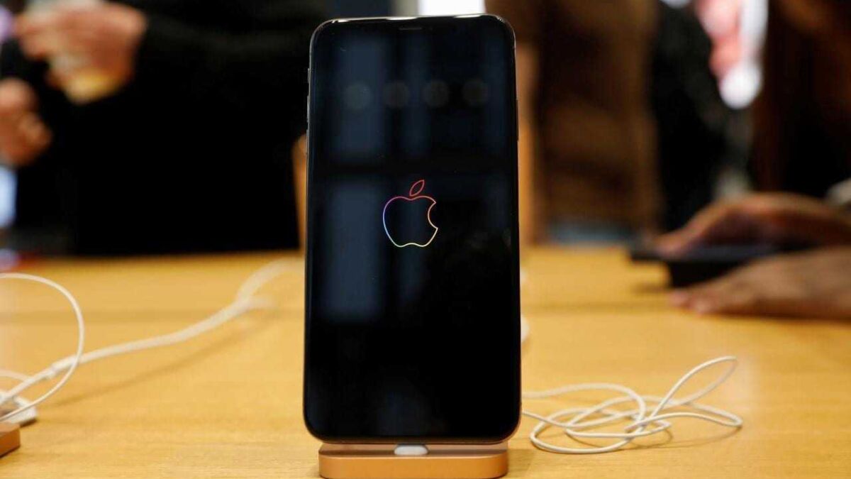 iPhone с отображением логотипа Apple на экране и подставкой золотого цвета