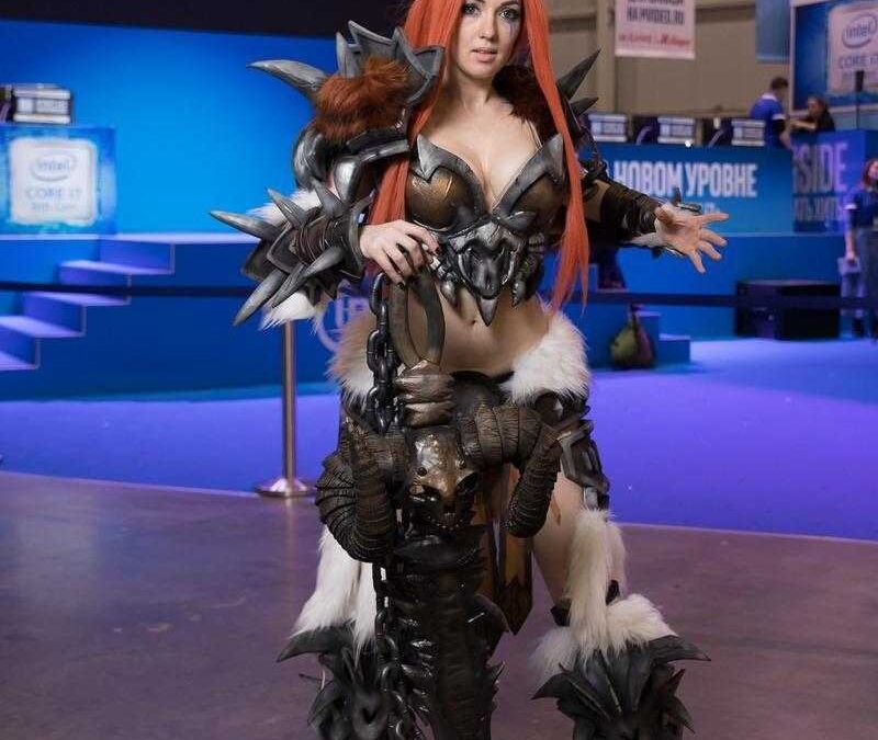 Косплей девушки в доспехах из игры World of Warcraft с длинными рыжими волосами и пушистыми лапами на торсе и ногах
