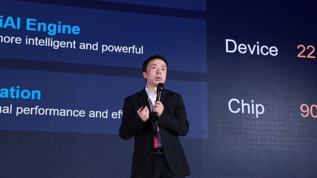 Спикер в черном костюме держит микрофон на презентации Huawei HiAI 2.0