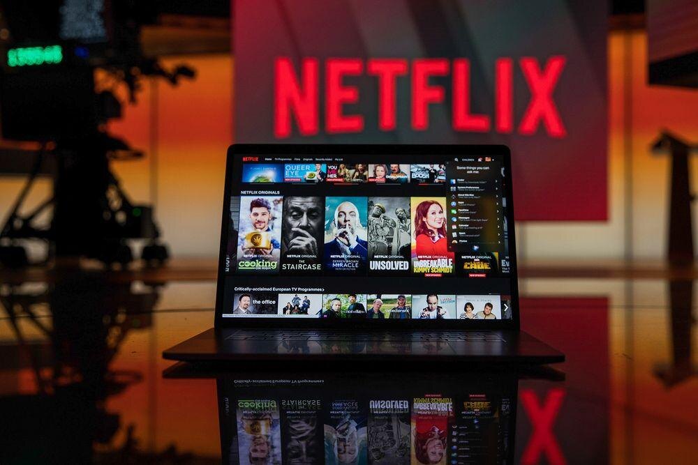 Планшет с интерфейсом Netflix на фоне логотипа Netflix