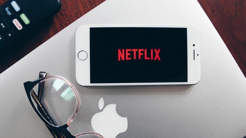 Телефон с логотипом Netflix и айпад на столе