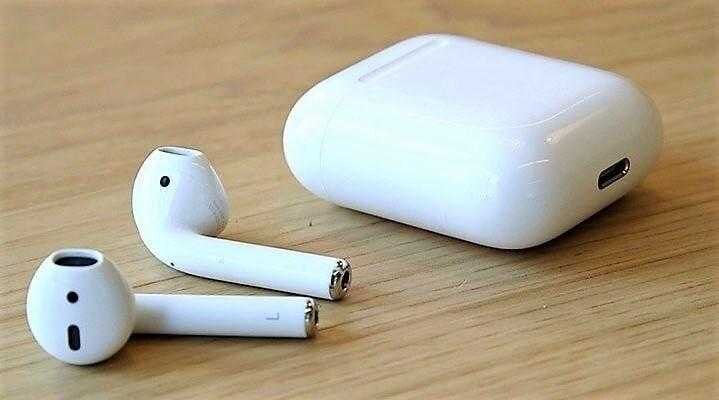 Комплект беспроводных наушников AirPods 2 и чехол на деревянной поверхности