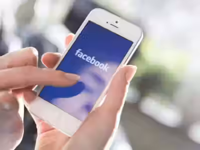 Айфон с логотипом Facebook в руке человека