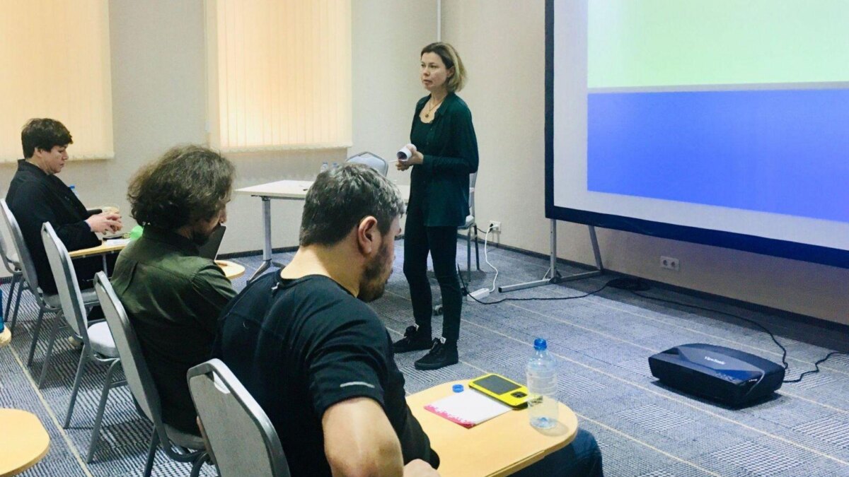 Женщина с ноутбуком возле презентационного экрана в конференц-зале для семинара по цифровой аналитике и монетизации