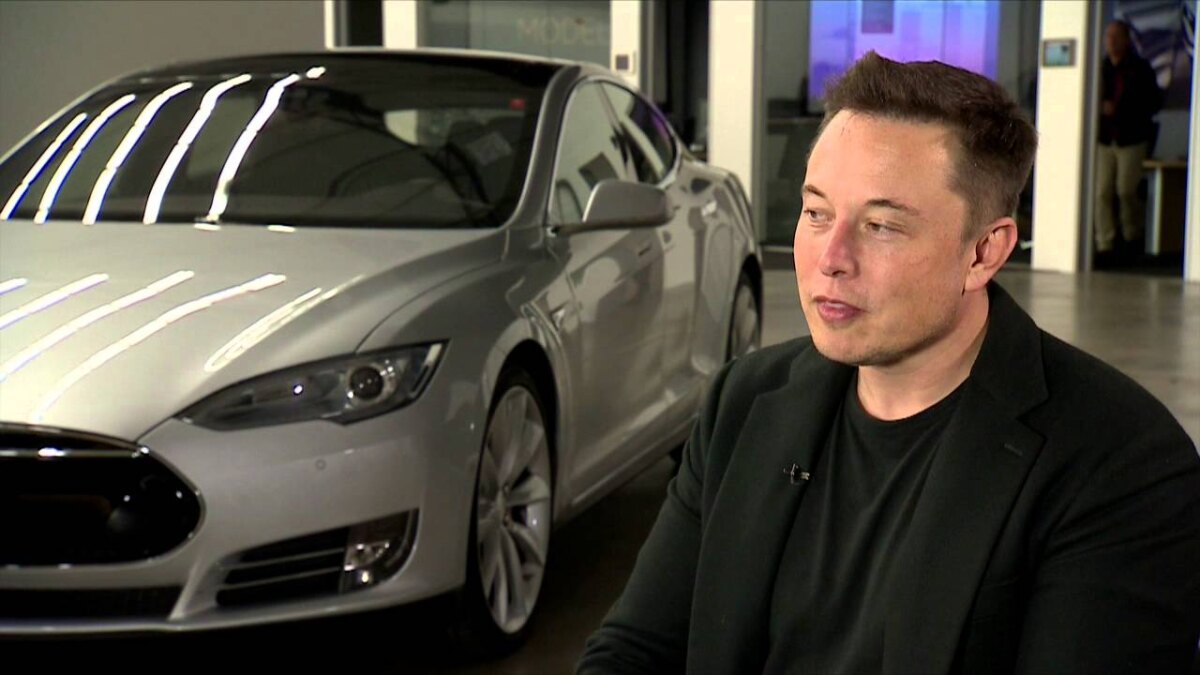 Робот Tesla с белым корпусом и черным лицевым экраном держит красную лоток с элементами