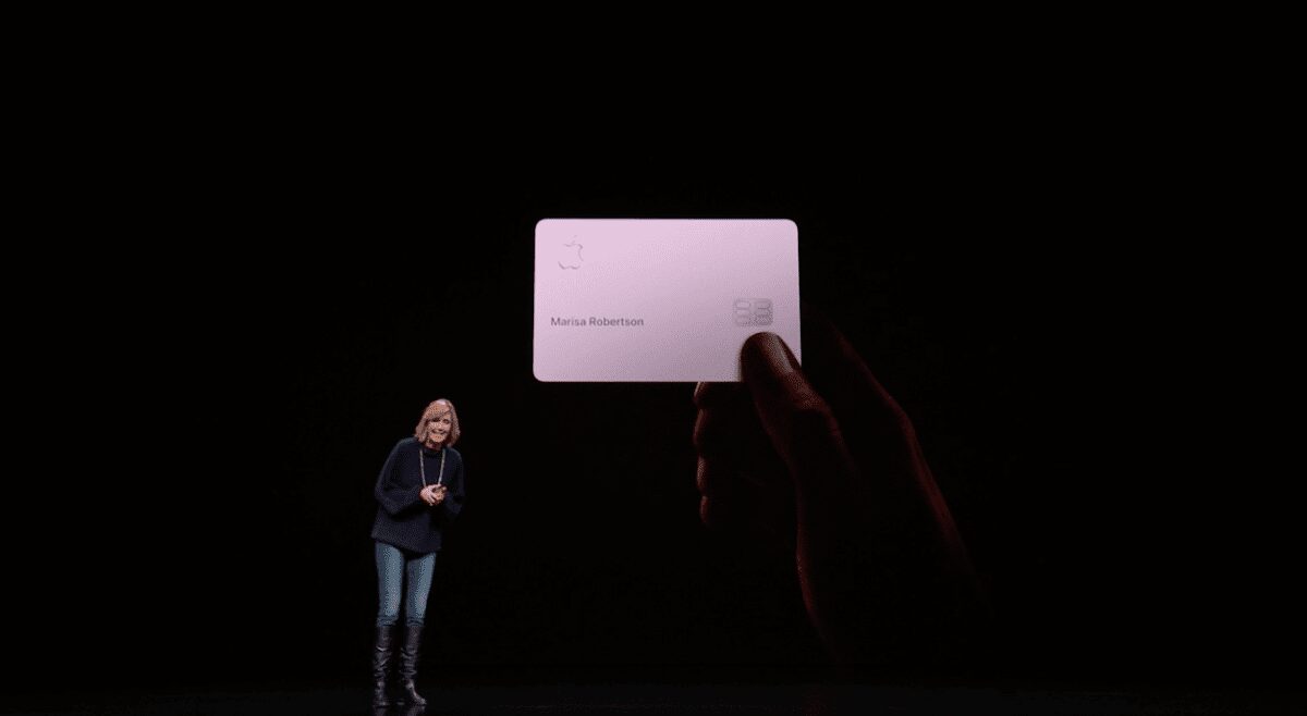 Рука держит виртуальную банковскую карту Apple Card на фоне презентации