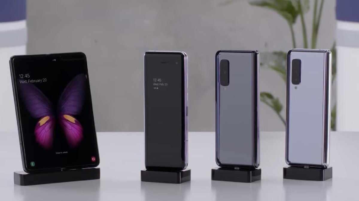 Четыре складных телефона Samsung в вертикальном положении на подставках