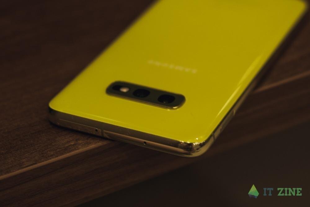 Желтый смартфон Samsung Galaxy S10 на деревянной поверхности