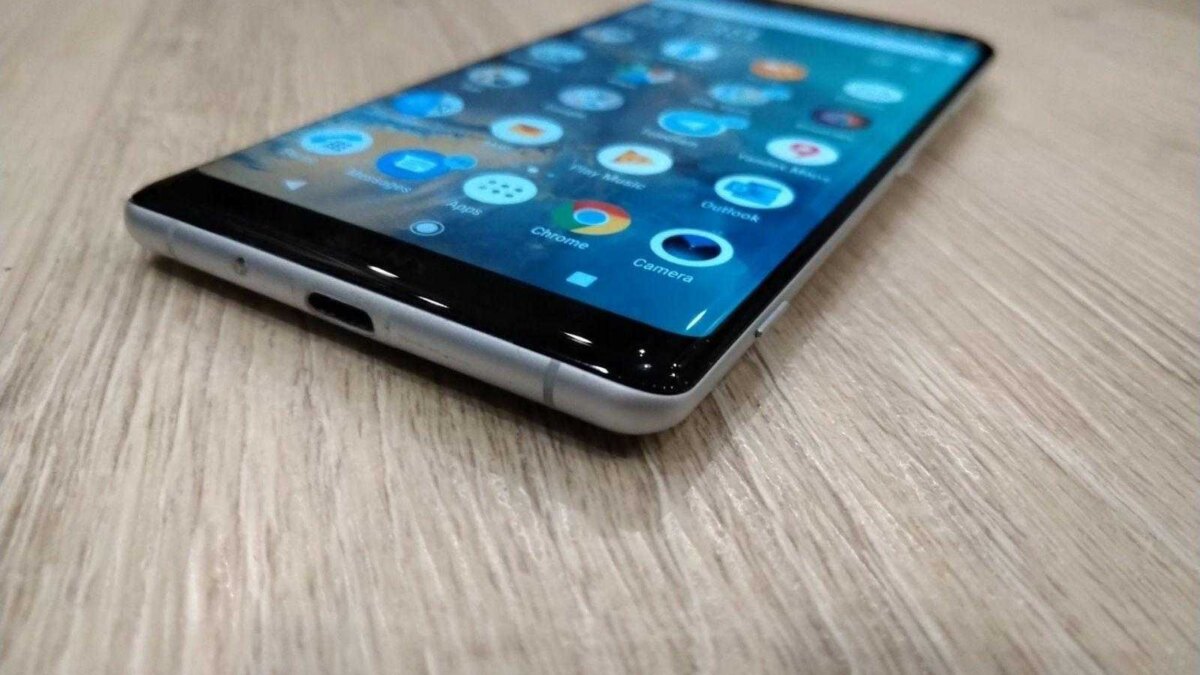 Смартфон iPhone с отображением рабочего стола на деревянной поверхности