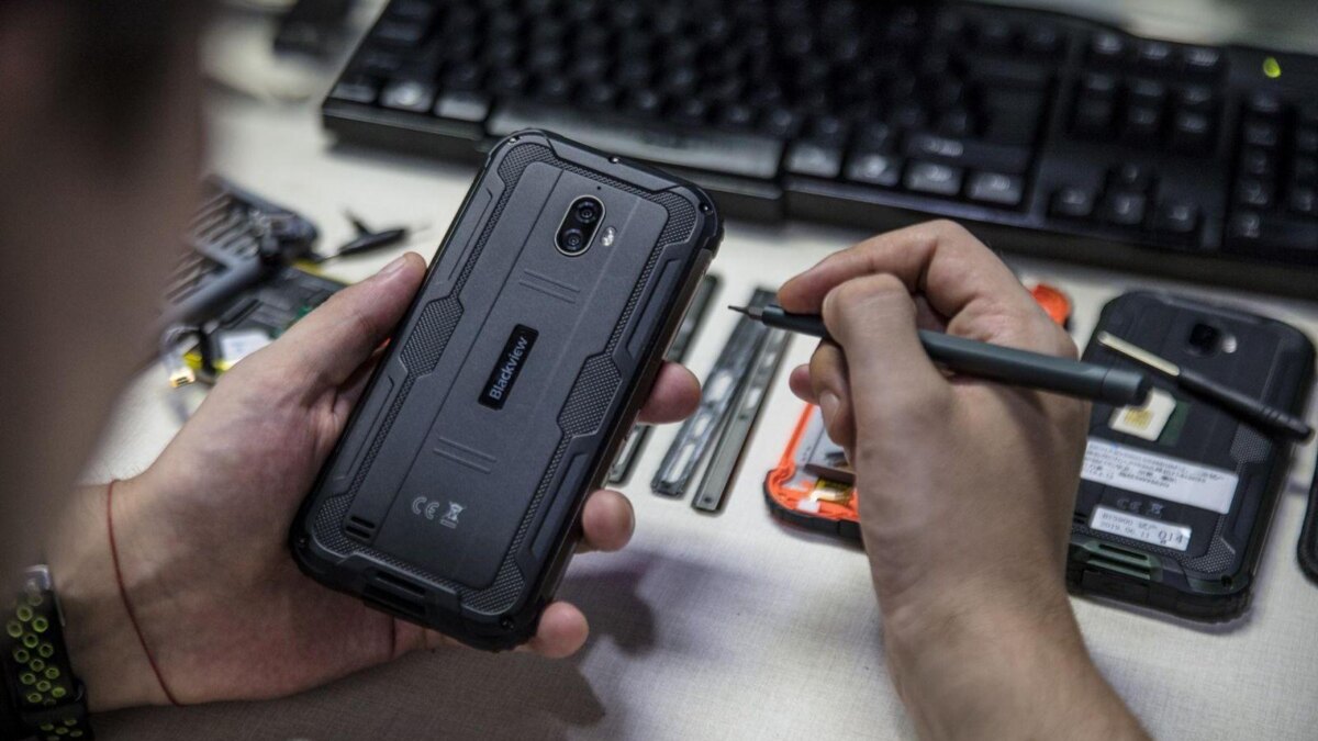 Человек ремонтирует Blackview сверхпрочному смартфон на рабочем месте