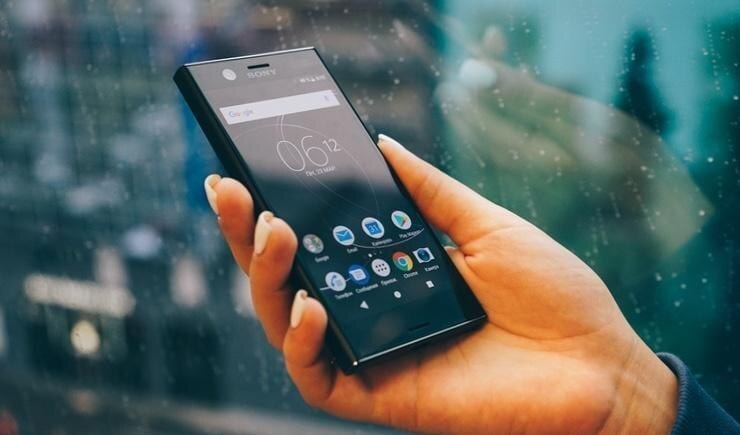 Рука держит смартфон Sony Xperia Compact с ярким экраном