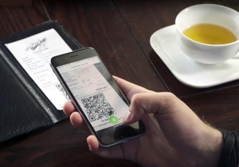 Человек с телефоном показывает QR-код для перевода чаевых