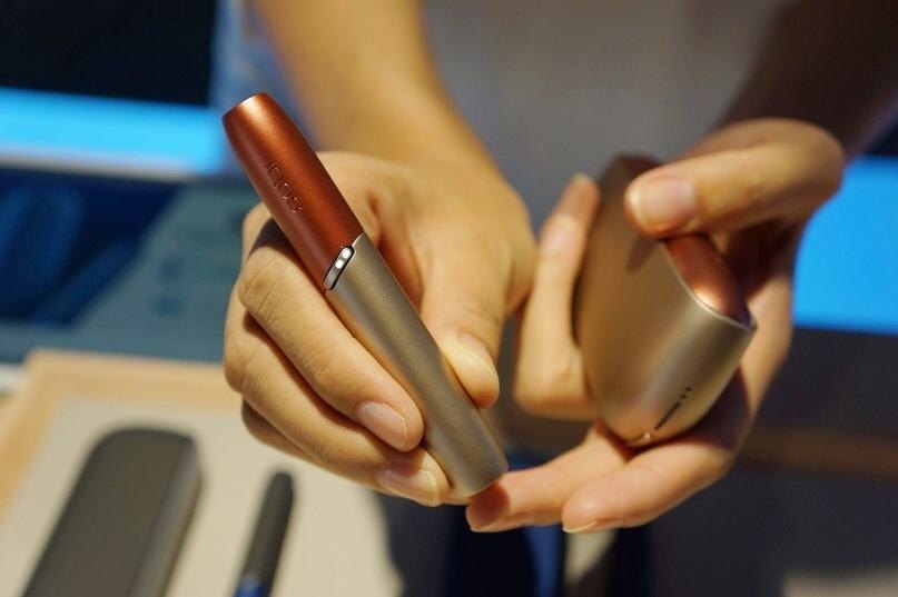 Человек держит устройство IQOS 3 DUOS и его контейнер