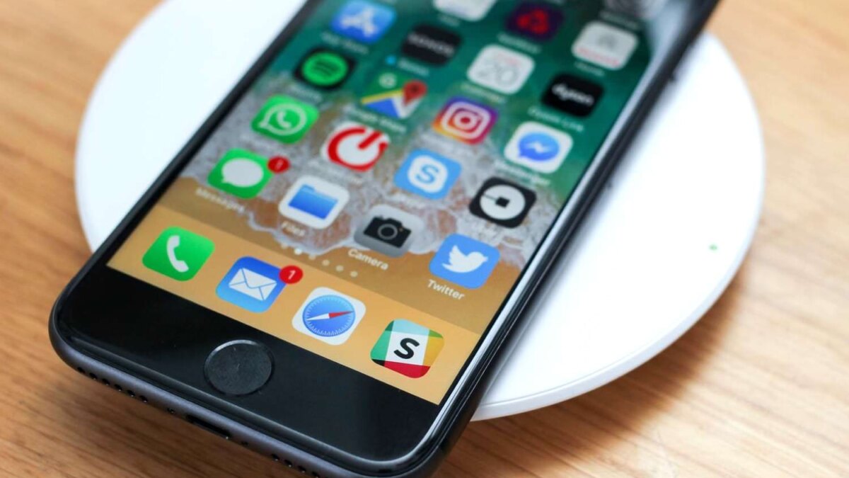 iPhone SE 2 на беспроводном зарядном устройстве на деревянной поверхности