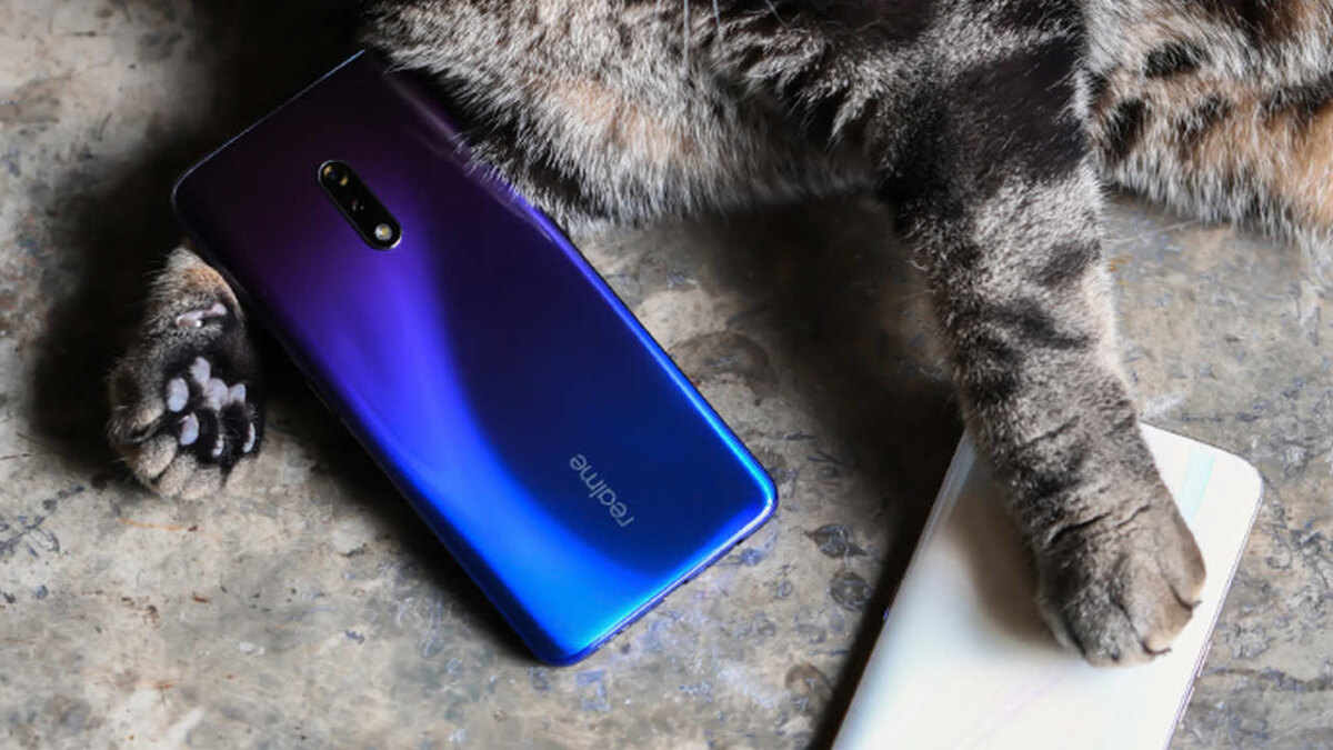 Смартфон Realme и коготь тигра на полу
