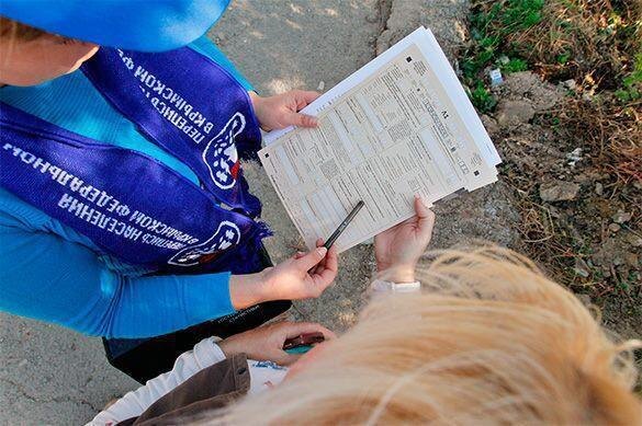 Люди держат документы и ручку на улице, один показывает заполненную анкету для переписи населения Россия