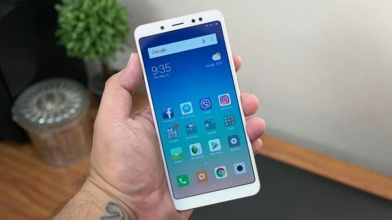 Смартфон на руке, отображается главный экран с иконками приложений