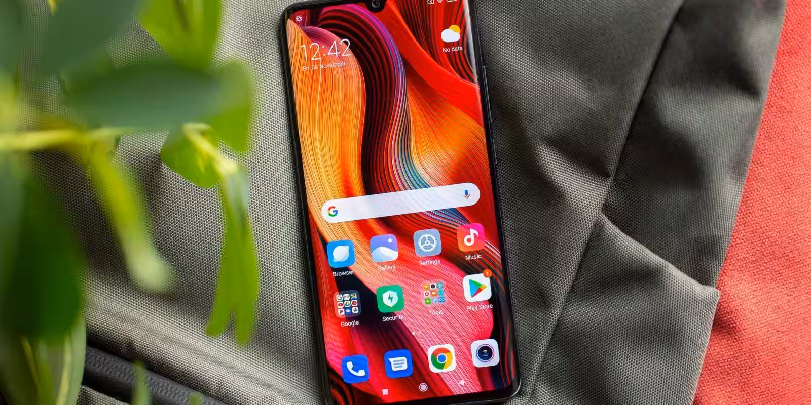 Смартфон Xiaomi на фоне чёрной ткани и зелени