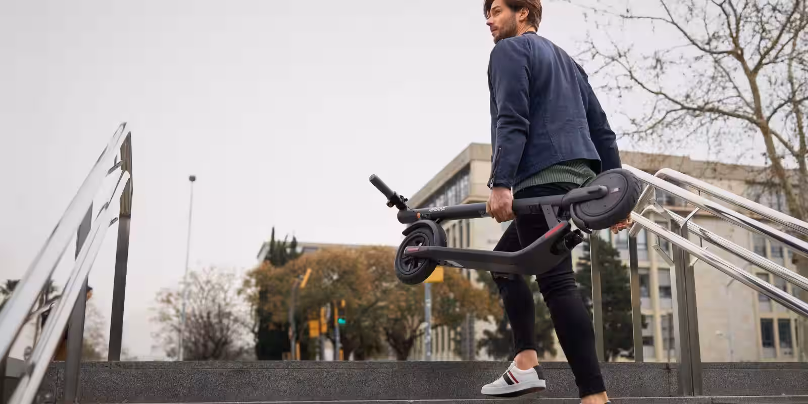 Мужчина с электросамокатом Segway KickScooter E22 на улице