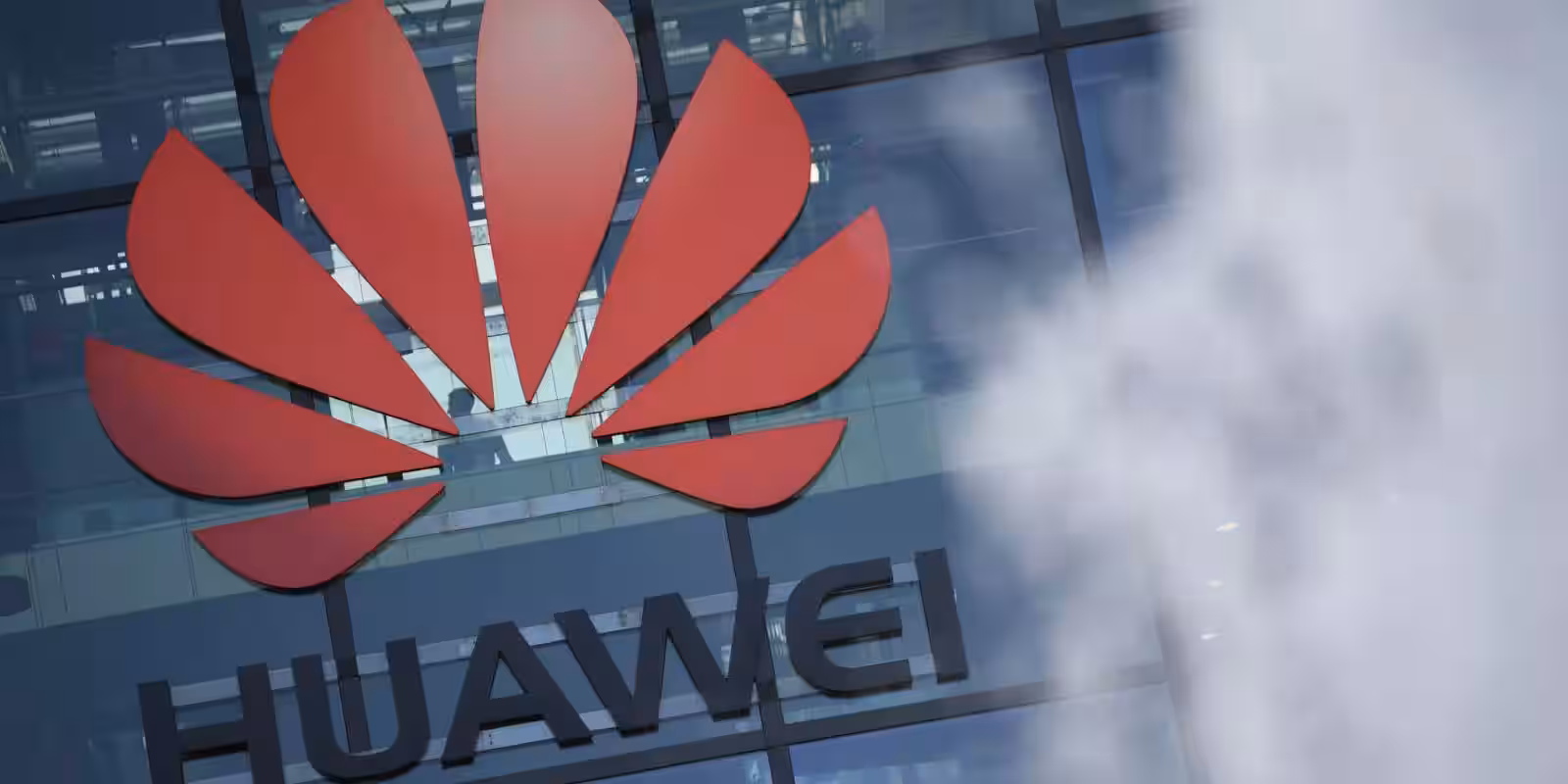 Логотип Huawei на стеклянной фасаде здания офисов