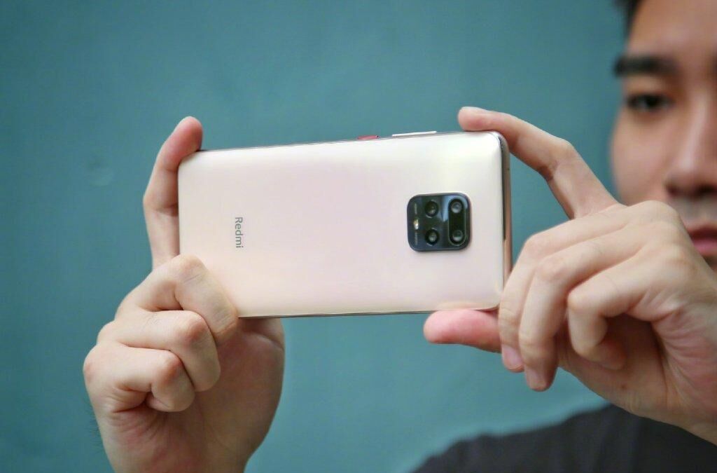 Человек фотографирует смартфон Redmi 10X Pro сбоку