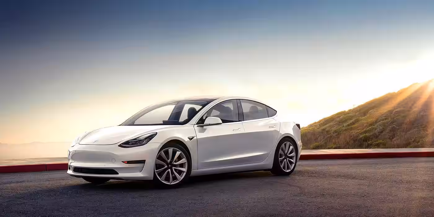 Электромобиль Tesla Model 3 на дороге на закате