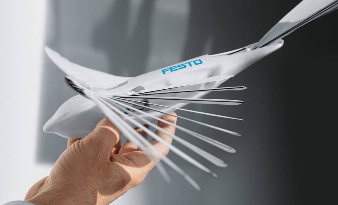 Рука держит конструкцию птицы-робота Festo с металлическими перьями