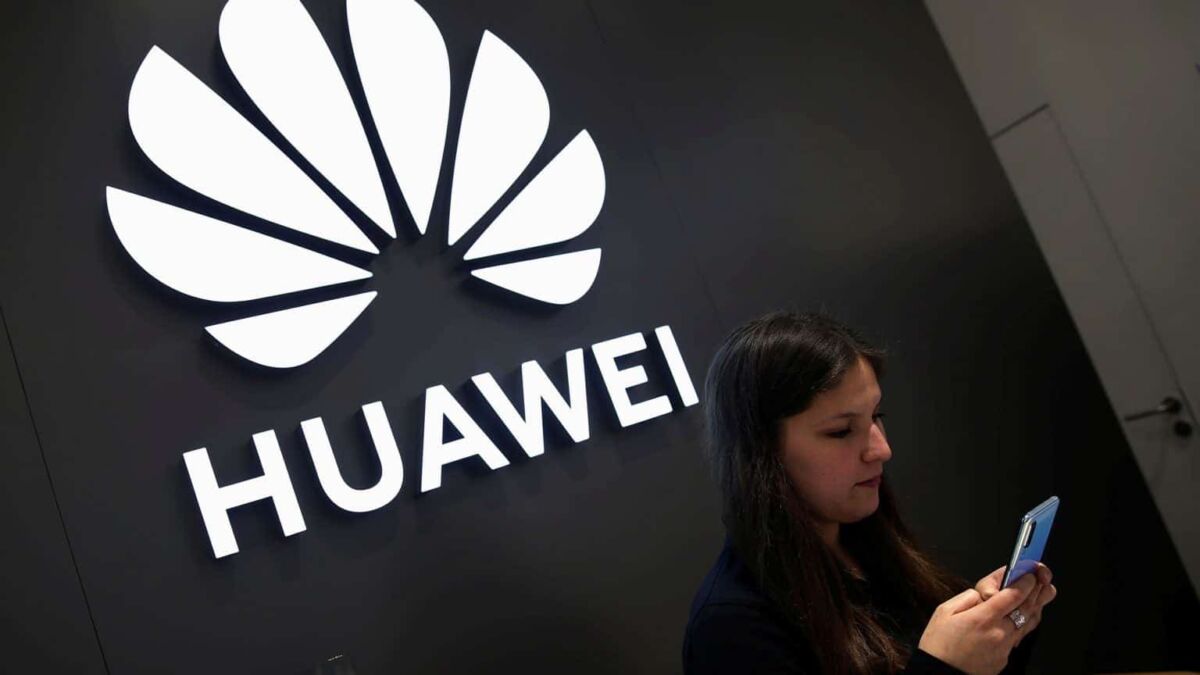 Женщина с мобильным телефоном возле логотипа Huawei