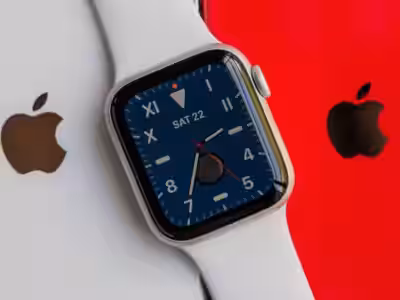 Умные часы Apple Watch SE с белым ремешком и черным дисплеем на фоне белого и красного устройств