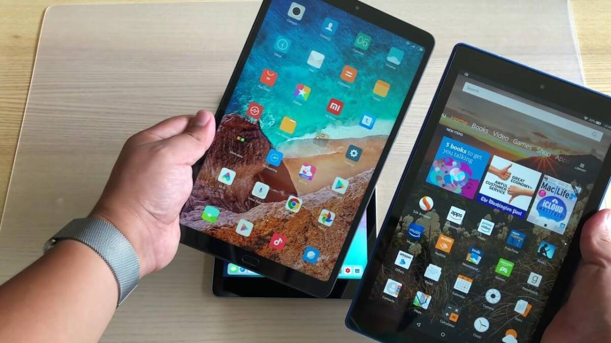 Два планшета Amazon с яркими интерфейсами в руках человека на демонстрации