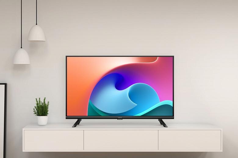 Современный плоский телевизор Realme на тумбе с цветным экраном