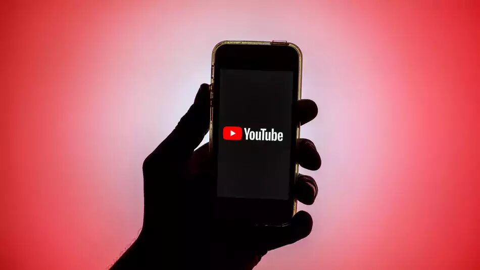 Рука держит смартфон с приложением YouTube на экране