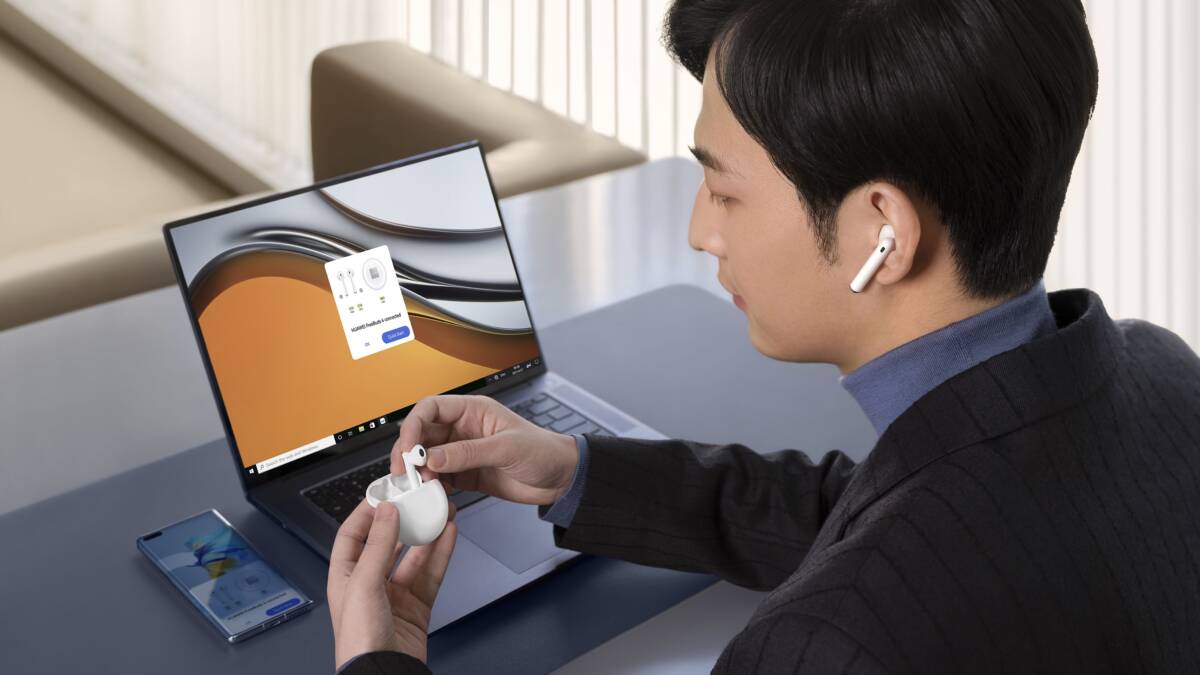 Мужчина с наушниками Huawei FreeBuds 4 использует ноутбук