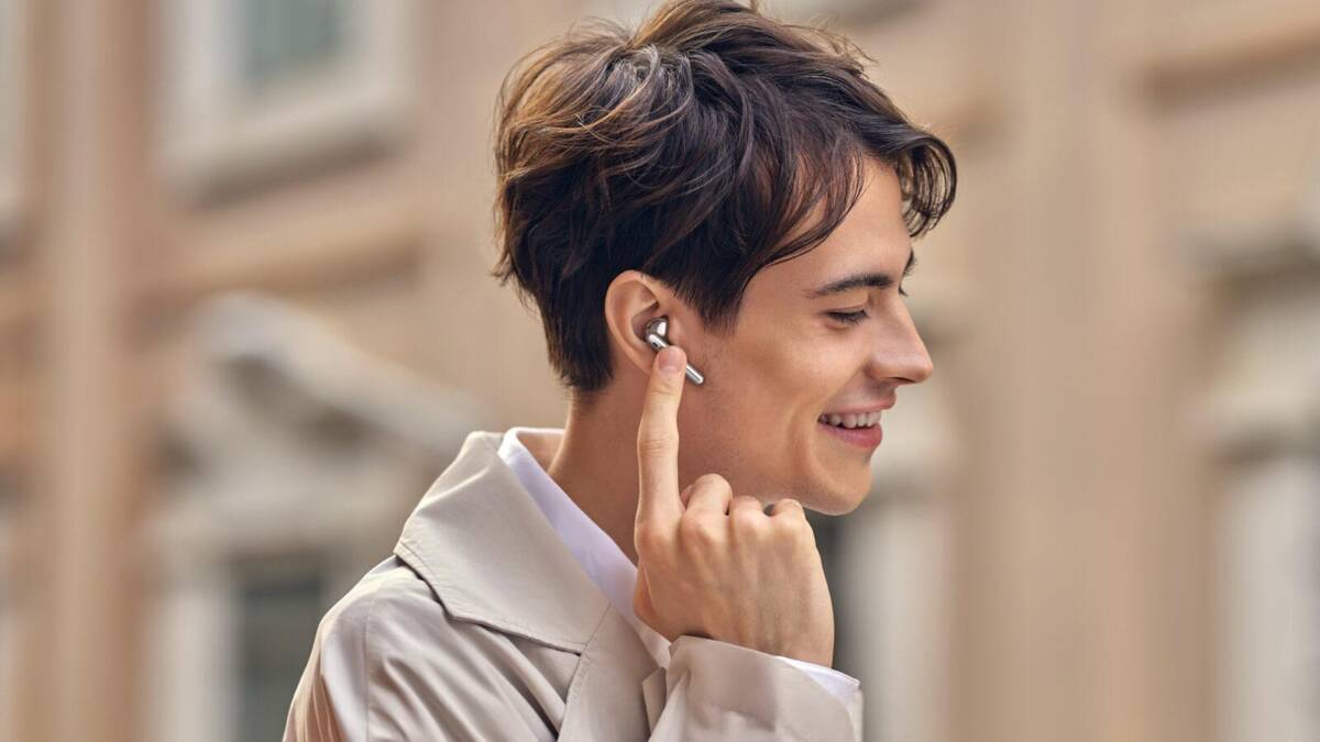 Мужчина вставляет Huawei FreeBuds 4 в ухо smiling