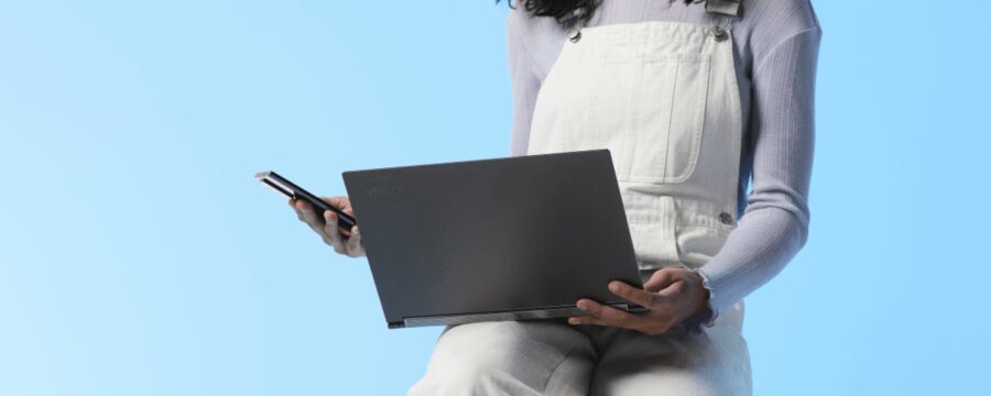 Пользователь с ноутбуком Lenovo и смартфоном в руках на голубом фоне