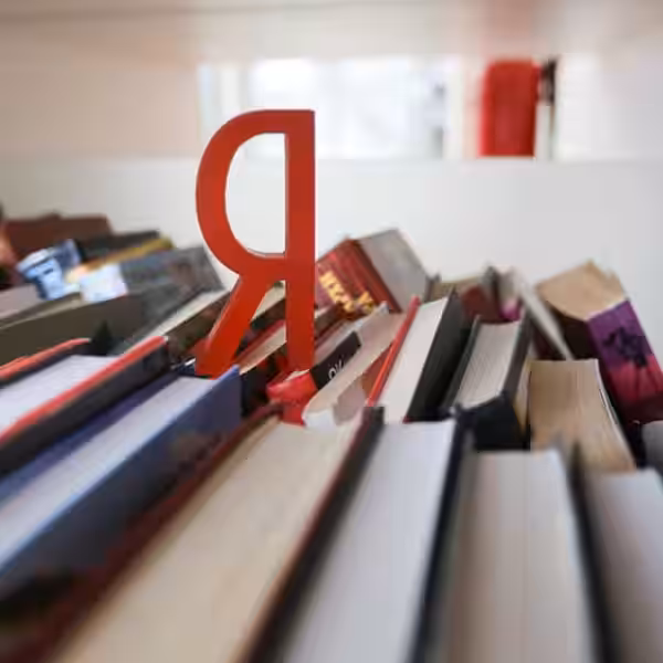 Книжная полка с книгами и заметной закладкой «Яндекс» среди изданий