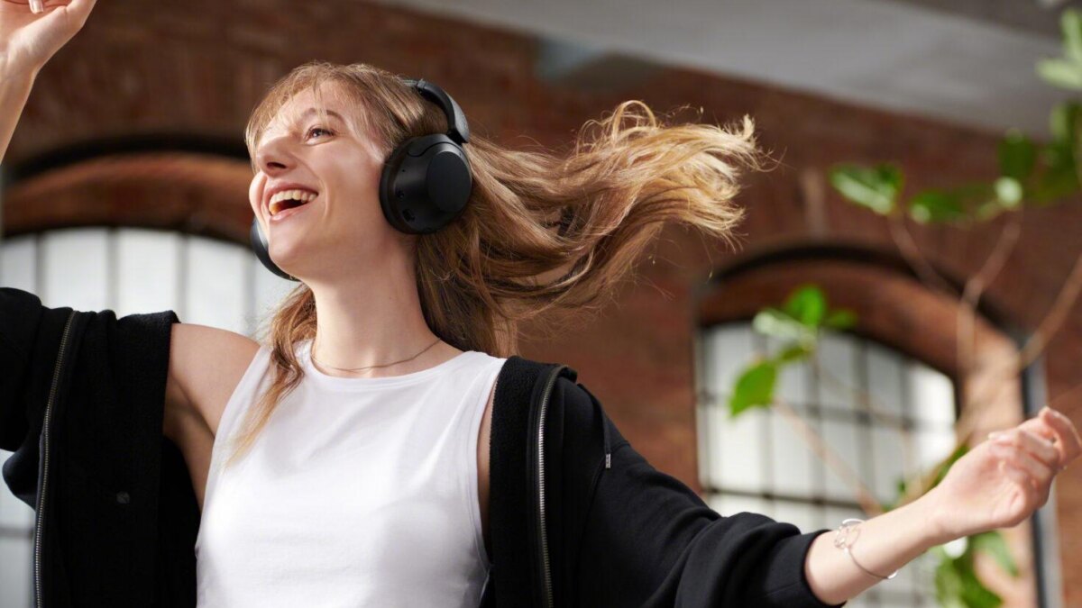 Молодая женщина с наушниками Sony WH-XB910N танцует