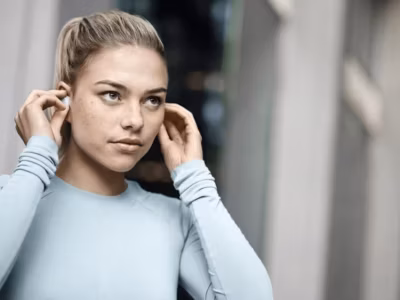 Девушка надевает беспроводные наушники Jabra Elite 4 Active