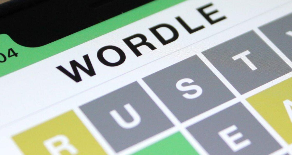 Экран смартфона с интерфейсом Wordle, биты зеленого и серого цвета