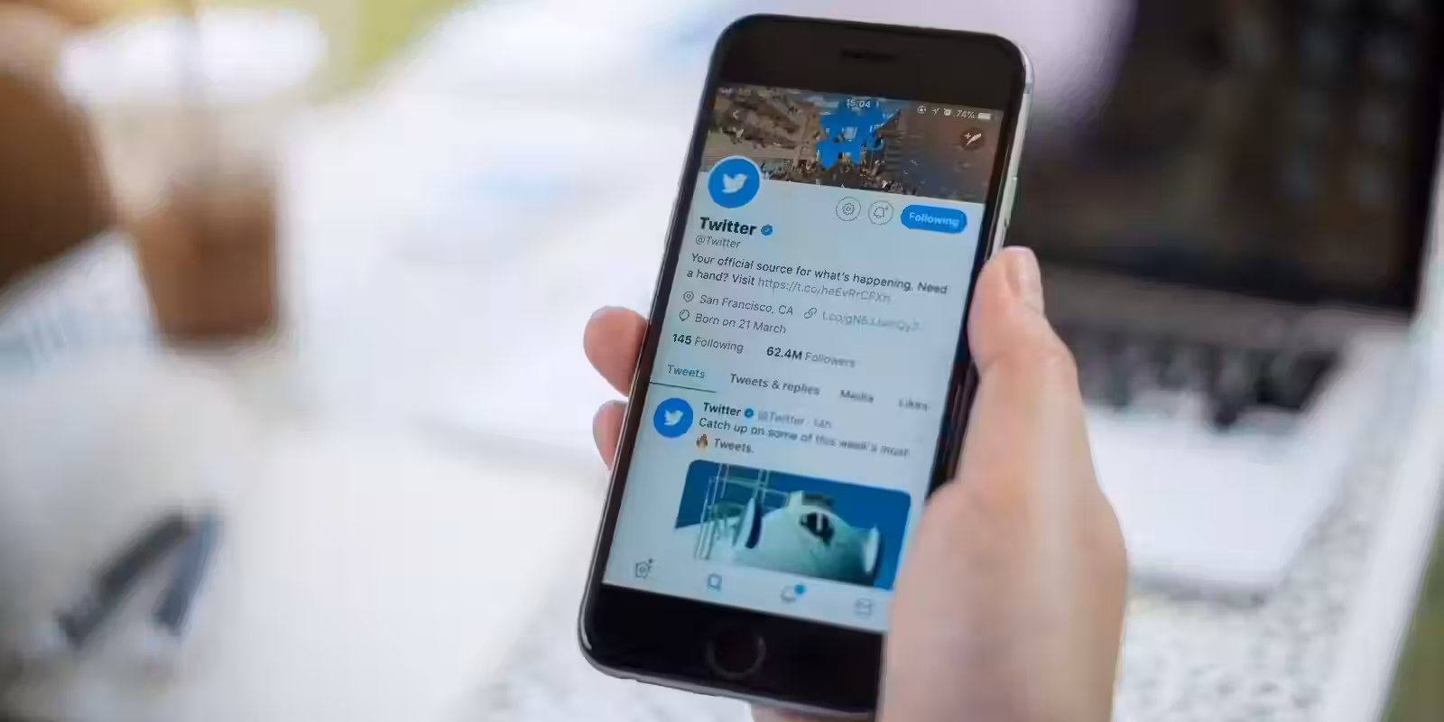 Рука держит смартфон iPhone с приложением Twitter на экране