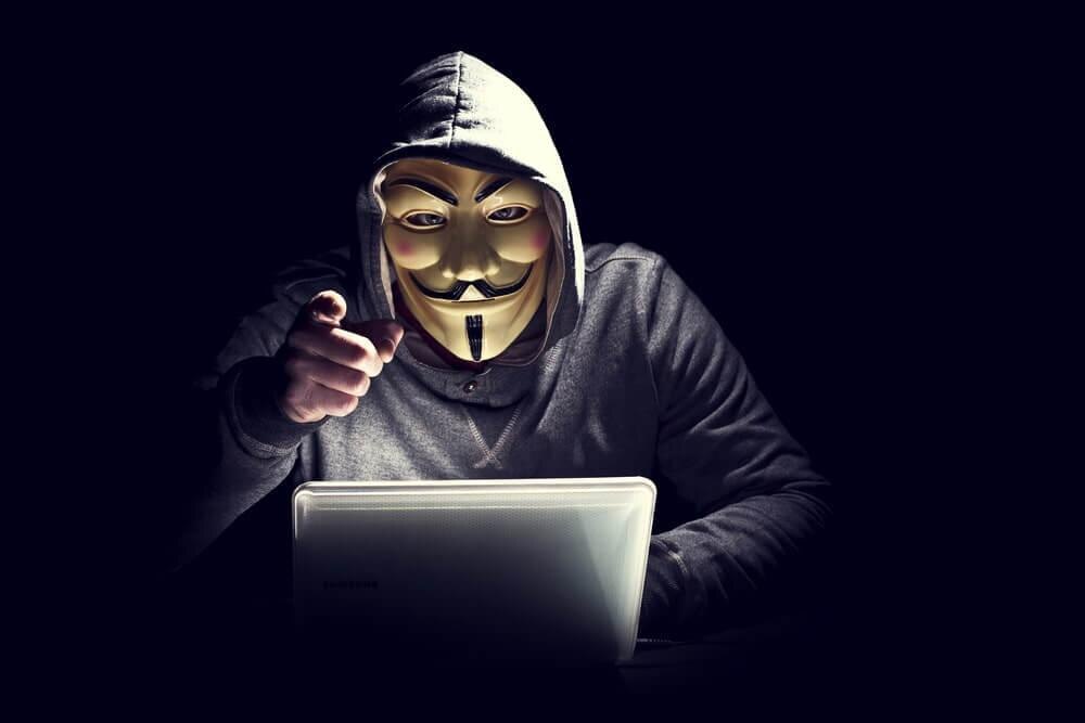 Злоумышленник в маске Gak en anonymous за компьютером