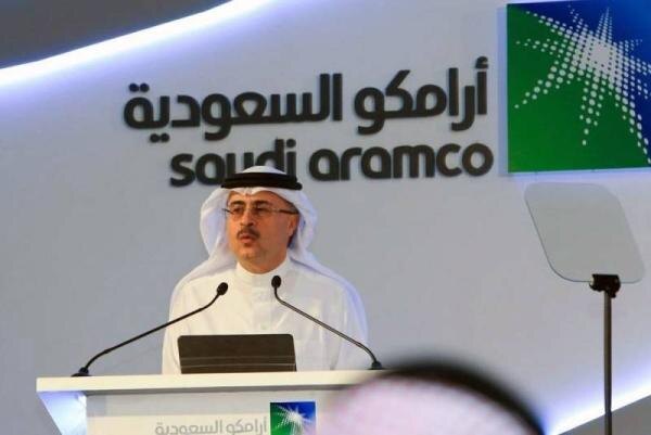 Мужчина на конференции с логотипом Saudi Aramco на заднем плане