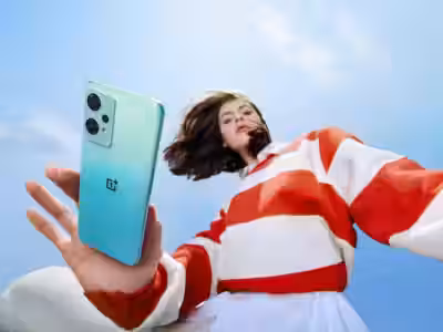 Молодая женщина с смартфоном OnePlus Nord 2T на улице в парке на фоне голубого неба
