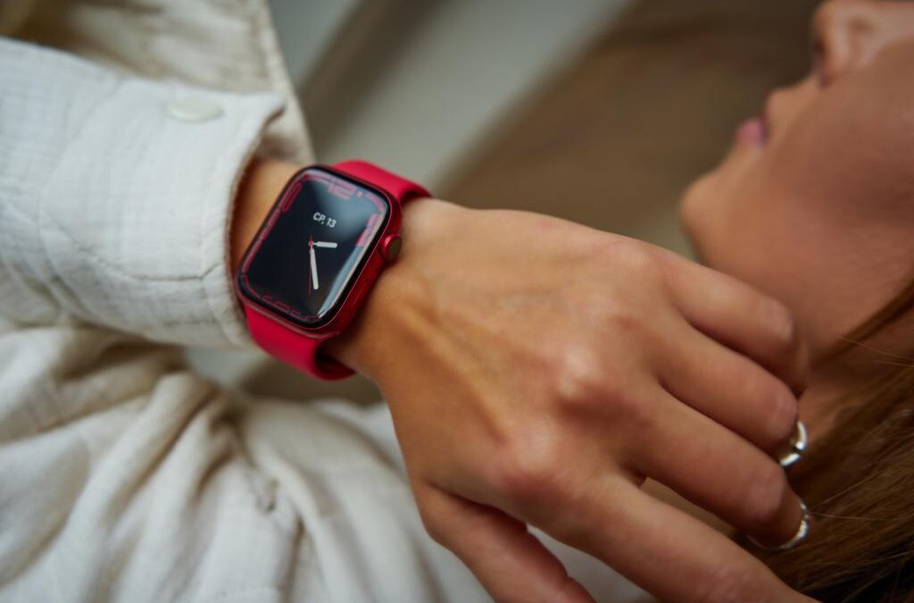 Женщина проверяет время на умных часах Apple Watch SE красного цвета