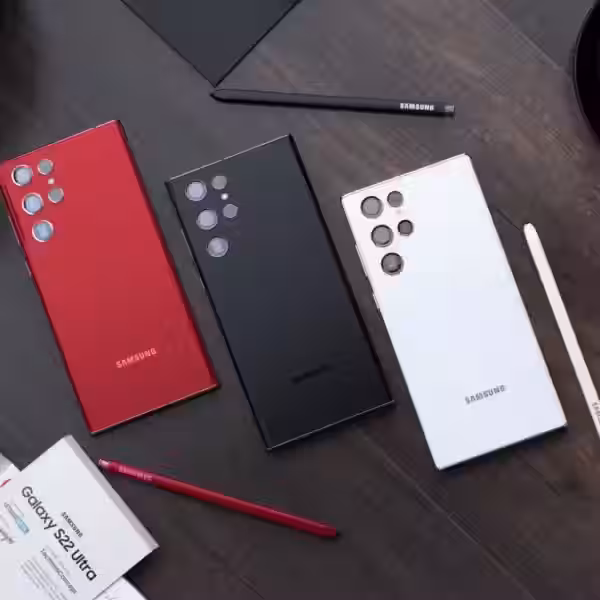 Три смартфона Samsung Galaxy S22 Ultra на столе, с ручками и бумагами