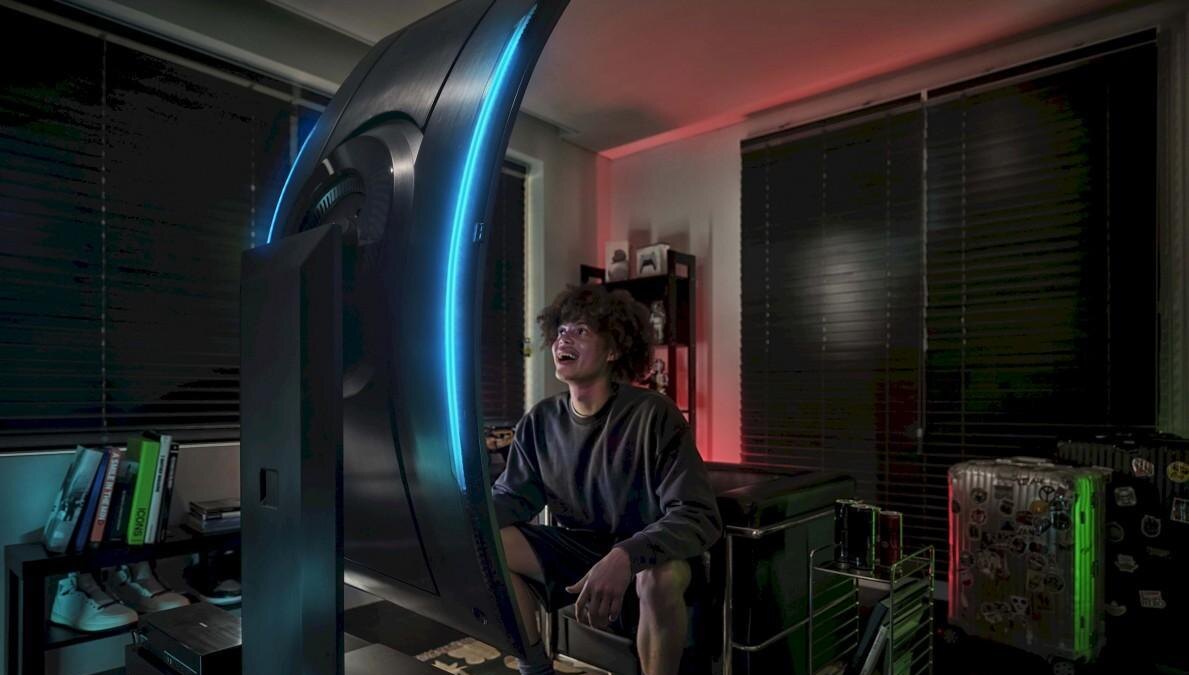 Геймер сидит перед большим изогнутым монитором Samsung Odyssey Ark